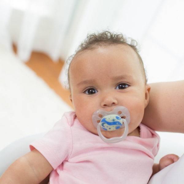 Baby in mother's arms with pacifier in mouth
