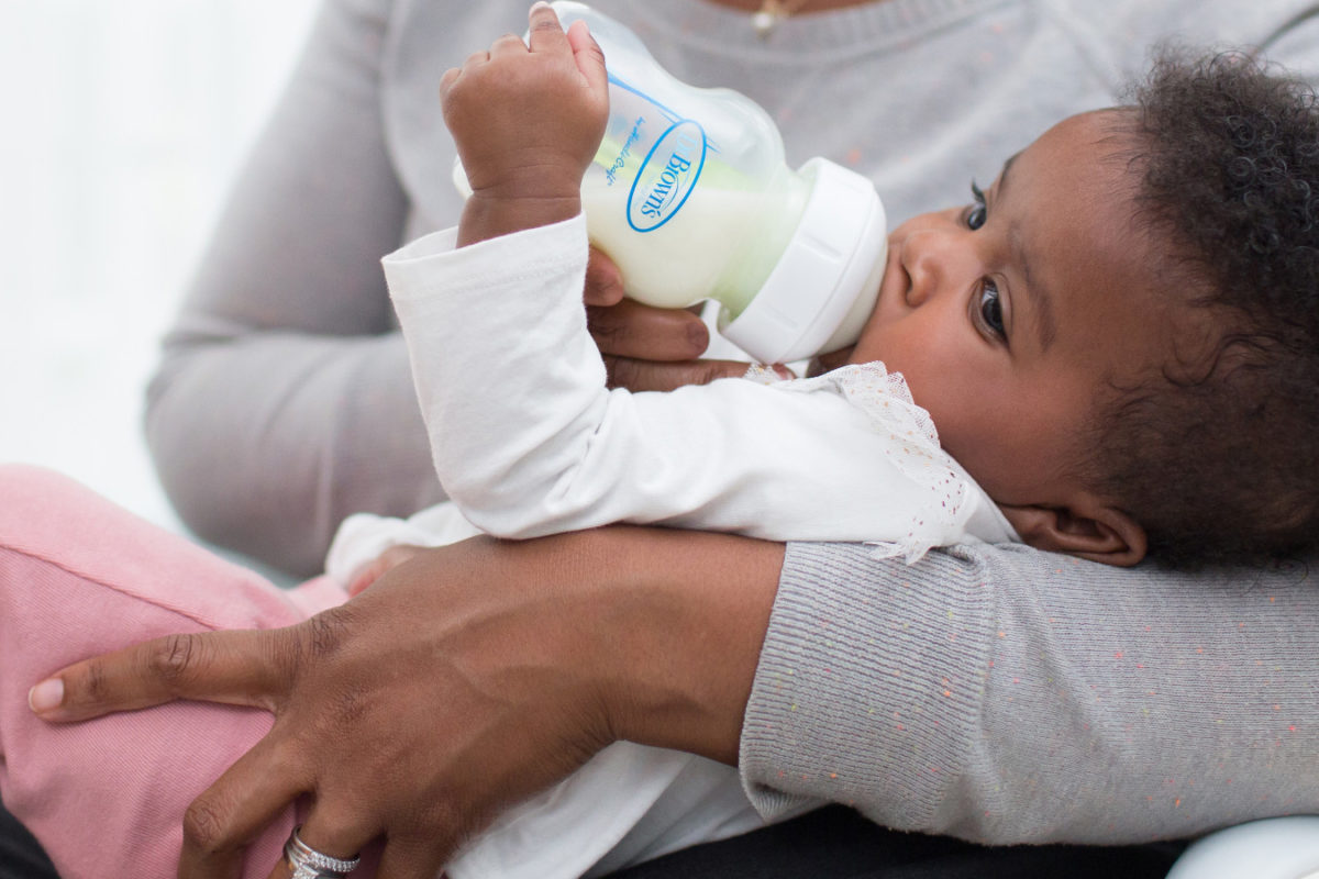 women feeding baby from baby bottle